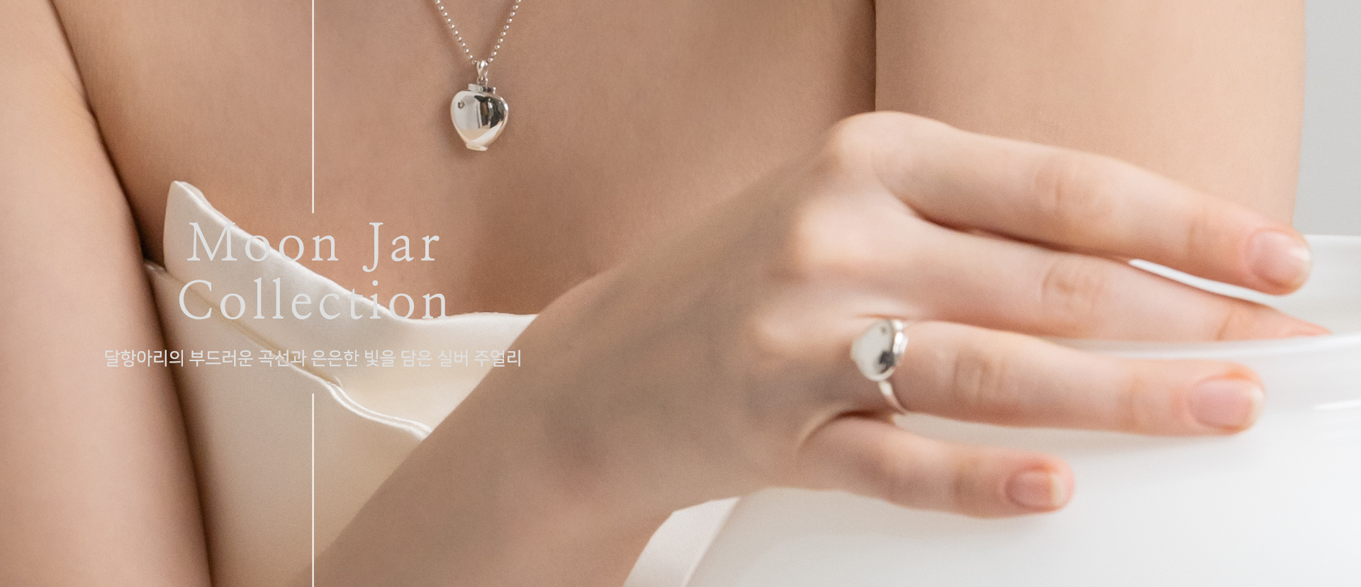 Model wearing CHAESY Moon Jar necklace and ring beside a white porcelain moon jar