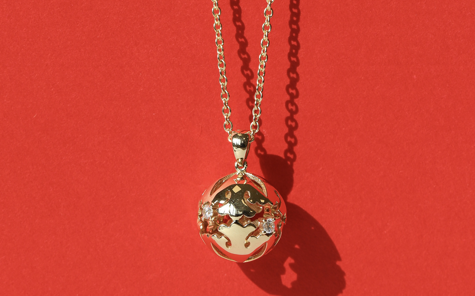 Jangseok gold-plated orb pendant necklace on red background